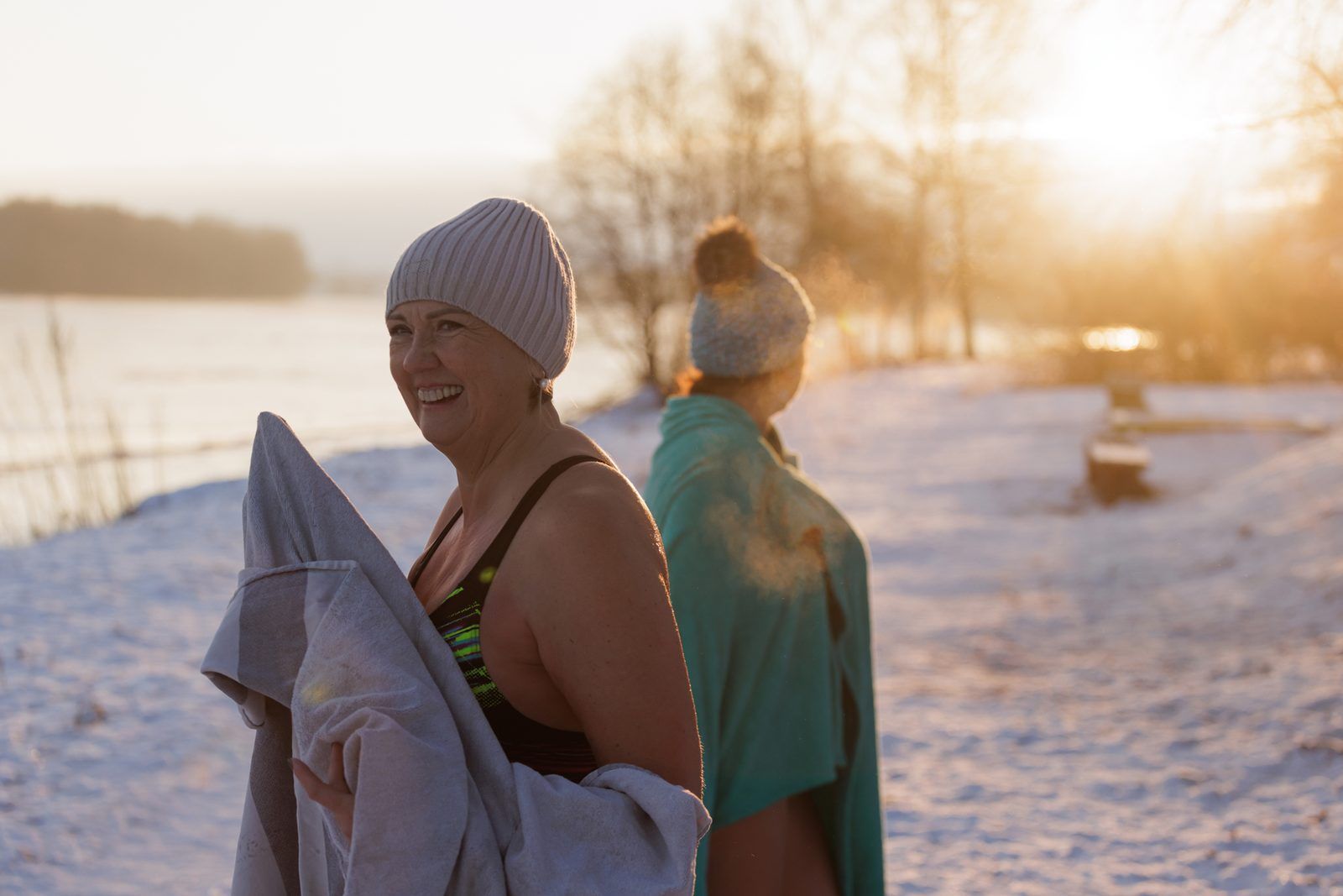 Kälteexposition: zwei Frauen am Flussufer bei Sonnenaufgang
